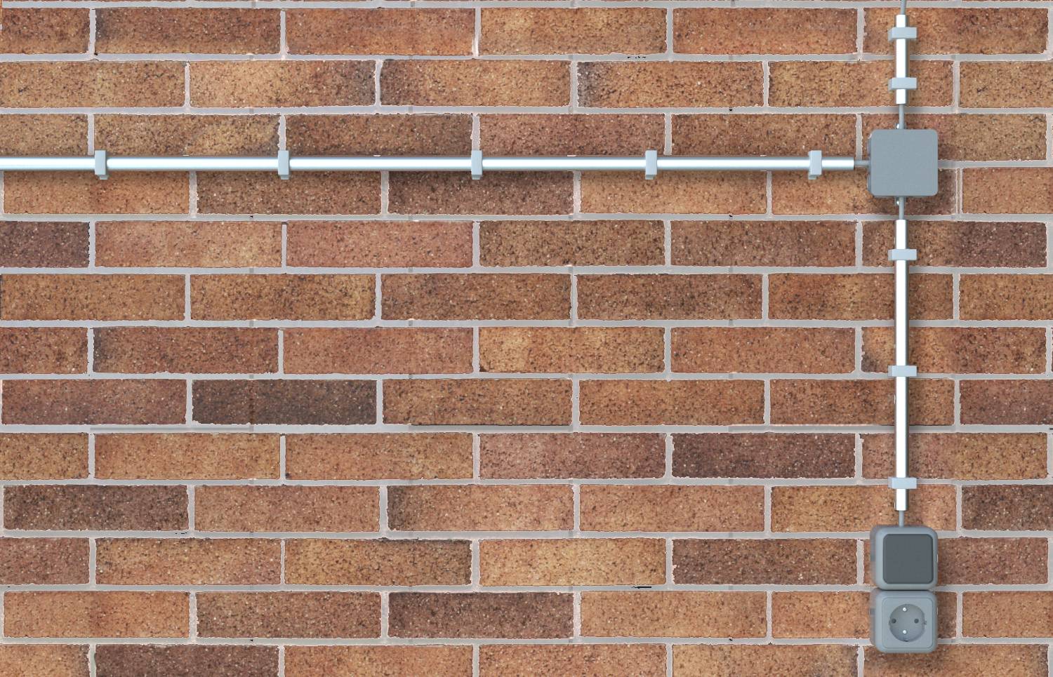 Außenwand aus Backstein mit freiliegender weißer Leitungsrohr-Installation, die horizontal und vertikal verläuft und an zwei grauen Elektrokästen und einer Steckdose endet.