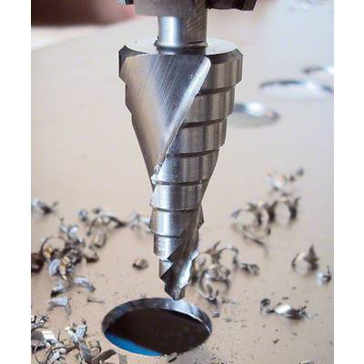 'Ein Kegelbohrer durchstößt ein Loch in einem Metallblech, umgeben von Metallspänen. Nahaufnahmen der Bohraction.'