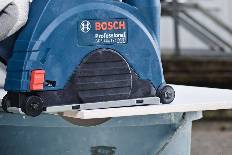 Elektrowerkzeug schneidet weiße Fliese. Nahaufnahme zeigt blaue Bosch Profi-Säge in Aktion. Handschuh hält die Platte.