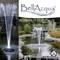 'BellAcqua Light Fountain' zeigt eine beleuchtete Wasserfontäne in einem Teich. Der Hintergrund zeigt Pflanzen und Steine.
