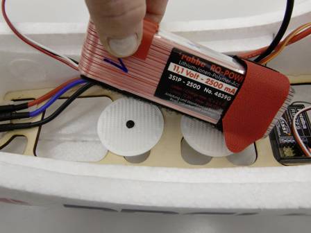 'Nahaufnahme eines Lithium-Ionen-Polymer-Akkus mit 11,1 Volt und 2500 mAh, der in eine weiße Halterung in einem Modellflugzeug eingesetzt wird.'