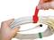 Eine Hand hält ein zusammengerolltes Kabel, während eine andere Hand ein rotes Klettband zum Befestigen um das Kabel anlegt.