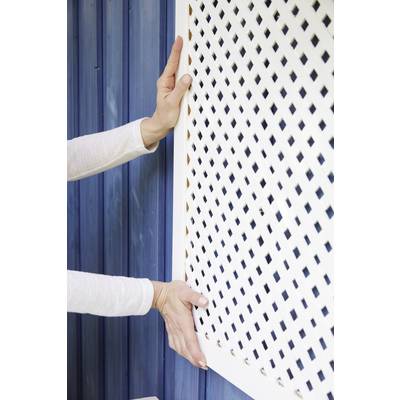 Eine Person montiert ein weißes Gitter vor einer blauen Holzwand.
