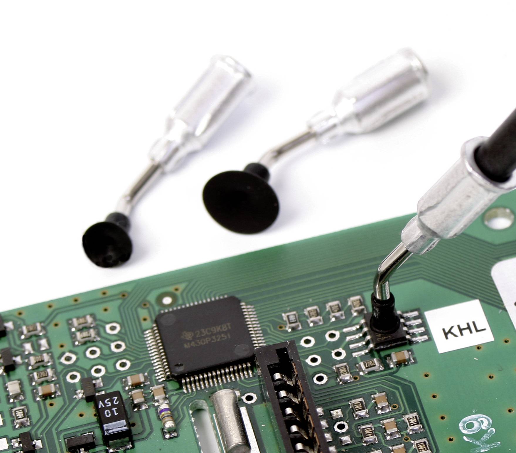 Nahaufnahme einer grünen Leiterplatte mit verschiedenen elektronischen Bauteilen und einem Schraubendreher im Hintergrund.