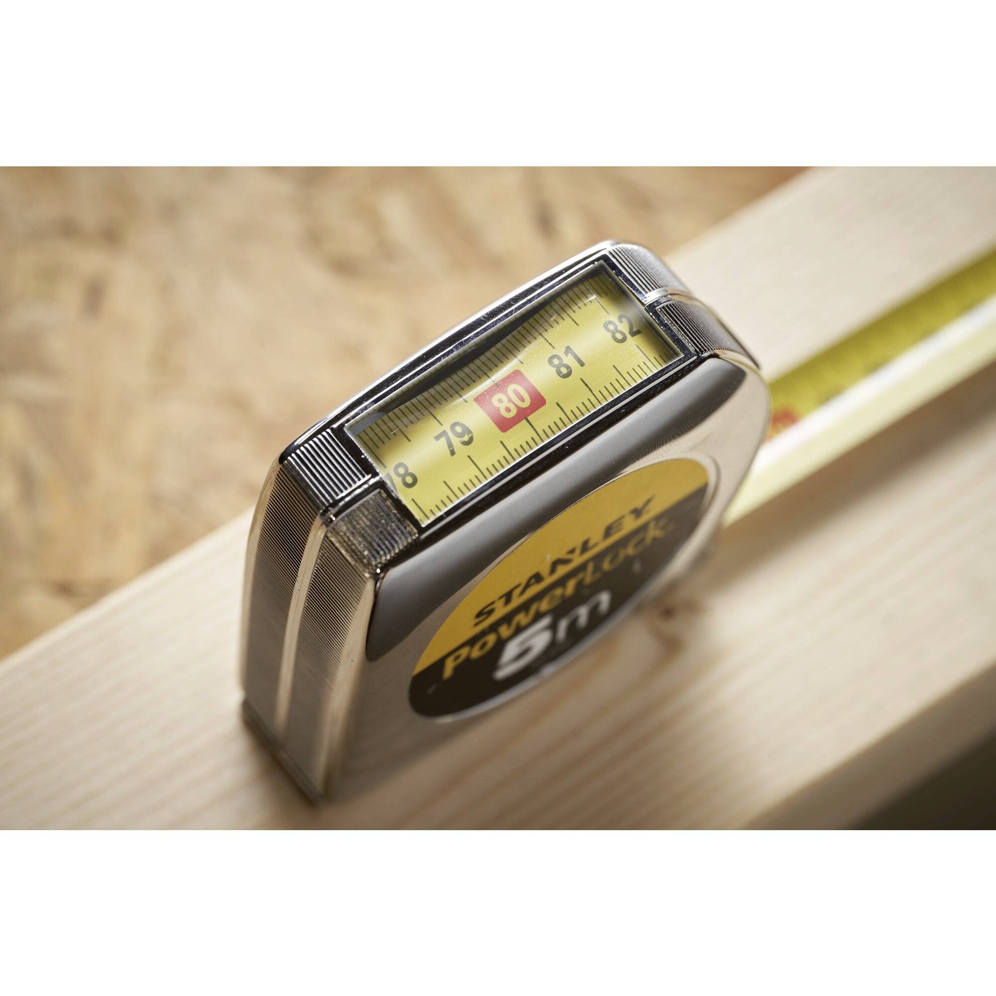 Ein Maßband auf einem Holzbrett zeigt 80 cm an. Es liegt auf einer Werkbank und wird für präzise Messungen verwendet.