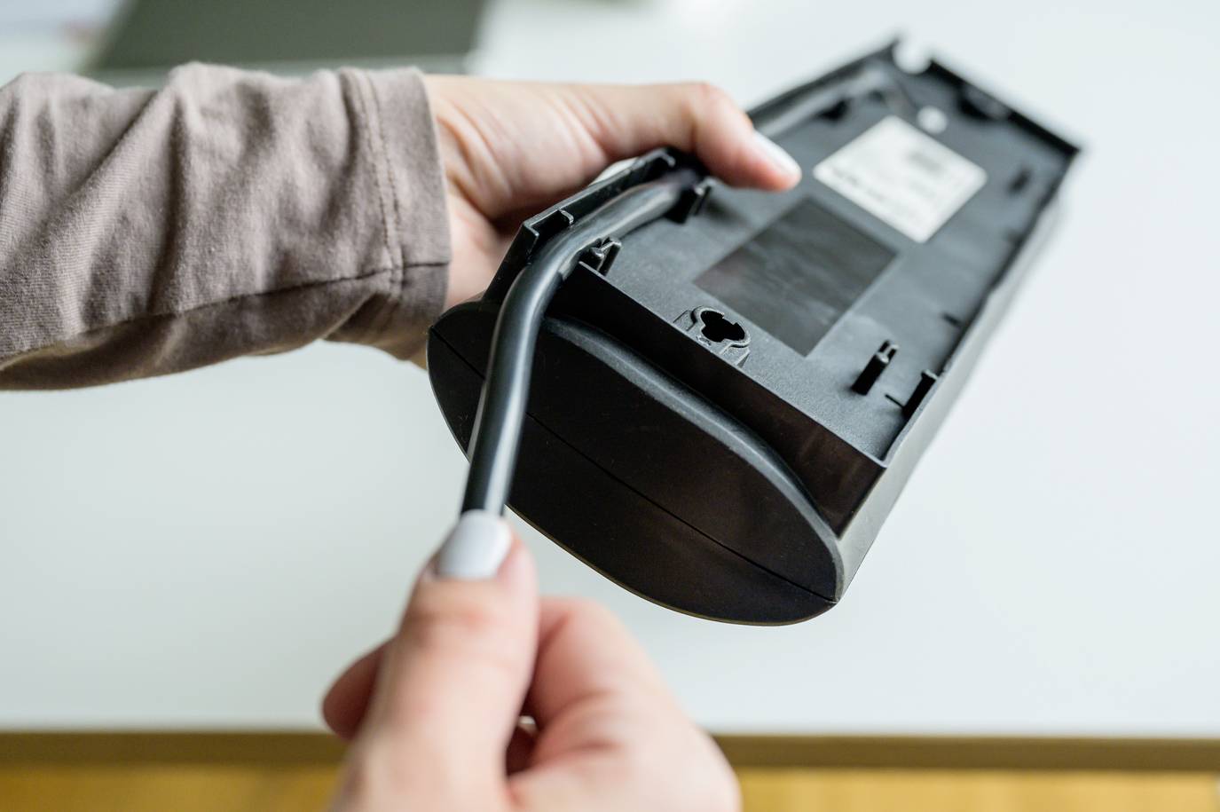 Eine Person hält einen Akkustaubsauger mit einer Düse in der Hand, bereitet ihn möglicherweise für den Einsatz vor oder reinigt ihn.