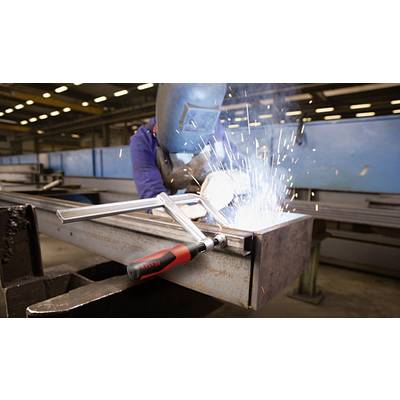 Ein Schweißer arbeitet an einem Metallstück mit Schutzmaske in einer Werkshalle. Funken fliegen, während er das Metall bearbeitet.