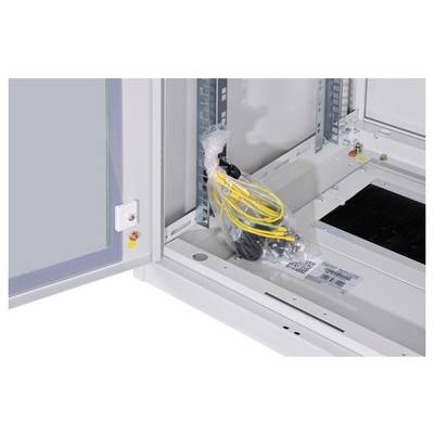 Schaltschrank innen, rechts liegt ein Beutel mit Kabeln. Links sind Montageschienen sichtbar. Es sind keine Geräte eingebaut.