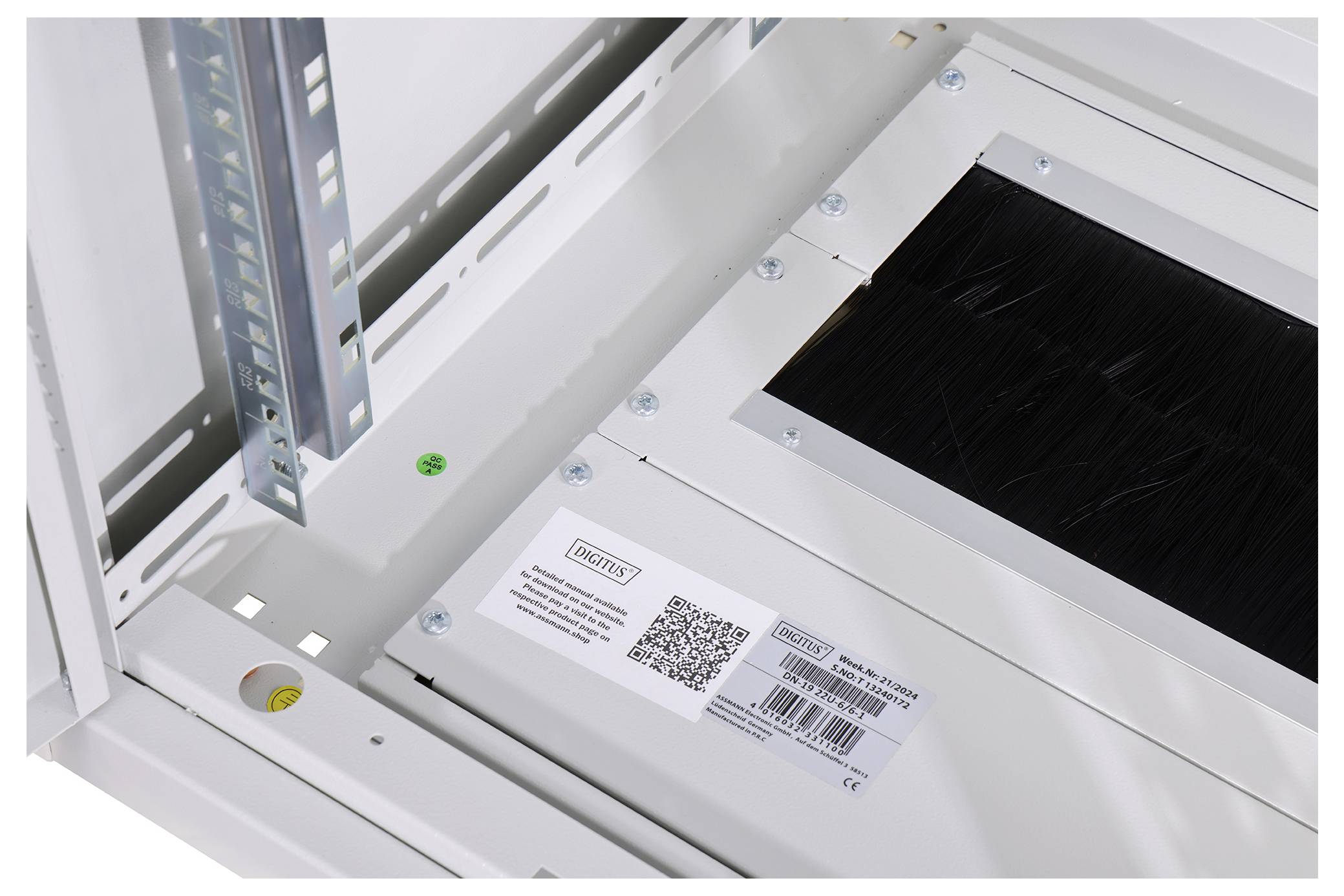 Elektronik-Rack mit Metallrahmen und schwarzem Kabeldurchlass. Ein QR-Code und Markenetikett sind auf einer Ecke sichtbar.