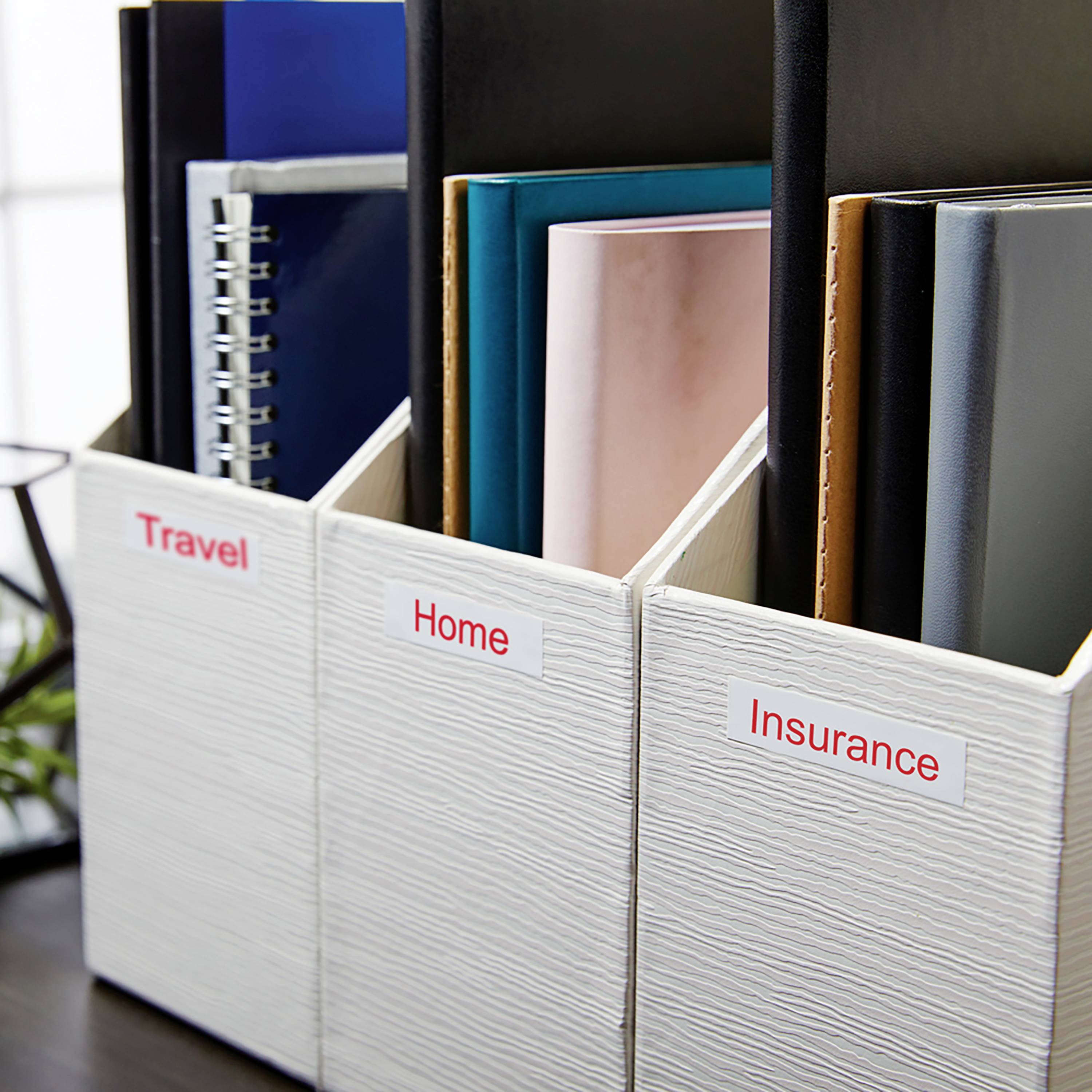 Mehrere Stehsammler mit Etiketten 'Travel', 'Home' und 'Insurance' enthalten Ordner in verschiedenen Farben, auf einem Schreibtisch.