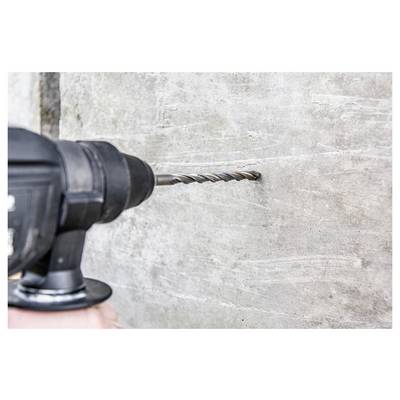 Nahaufnahme einer Elektrobohrmaschine mit einem Steinbohrer, der in eine Betonwand bohrt.
