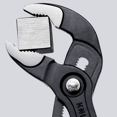 Eine Zange hält einen quadratischen Metallblock fest.