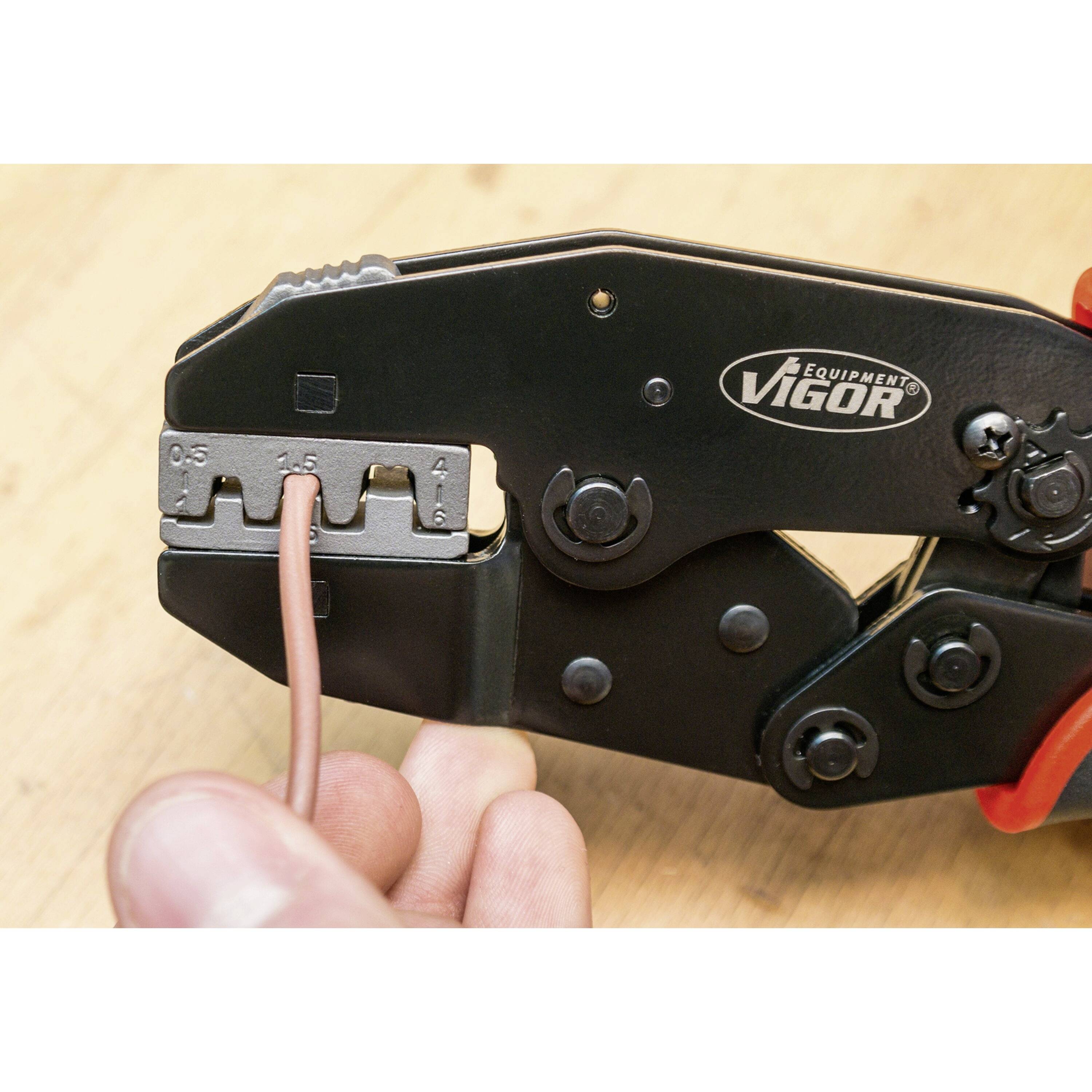 Eine Hand benutzt eine Crimpzange, um ein Kabel mit einer Metallhülse zu verbinden.