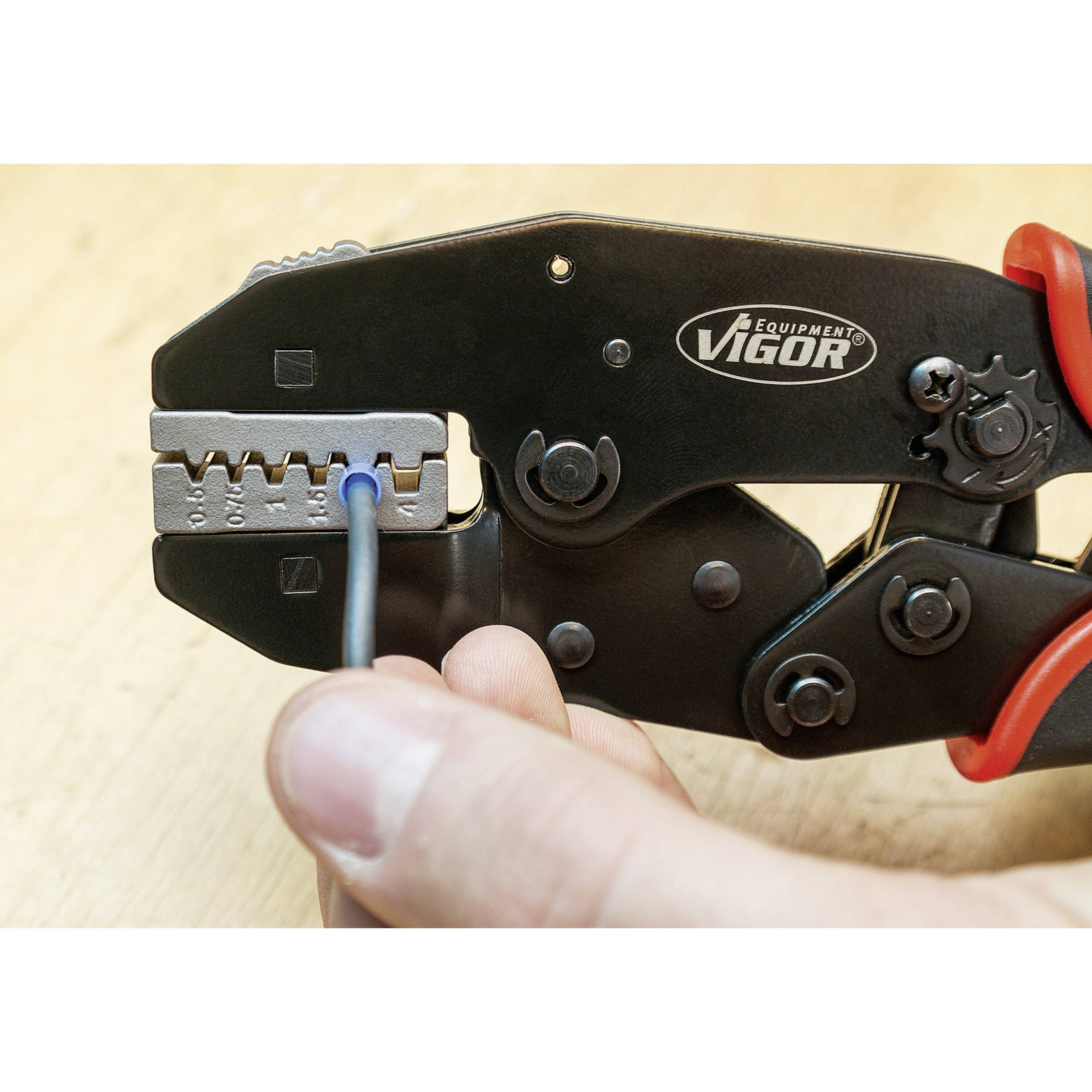 Nahaufnahme einer Hand, die ein Werkzeug zum Abisolieren von Kabeln verwendet. Das Werkzeug greift ein blaues Kabel, um die Isolierung zu entfernen.