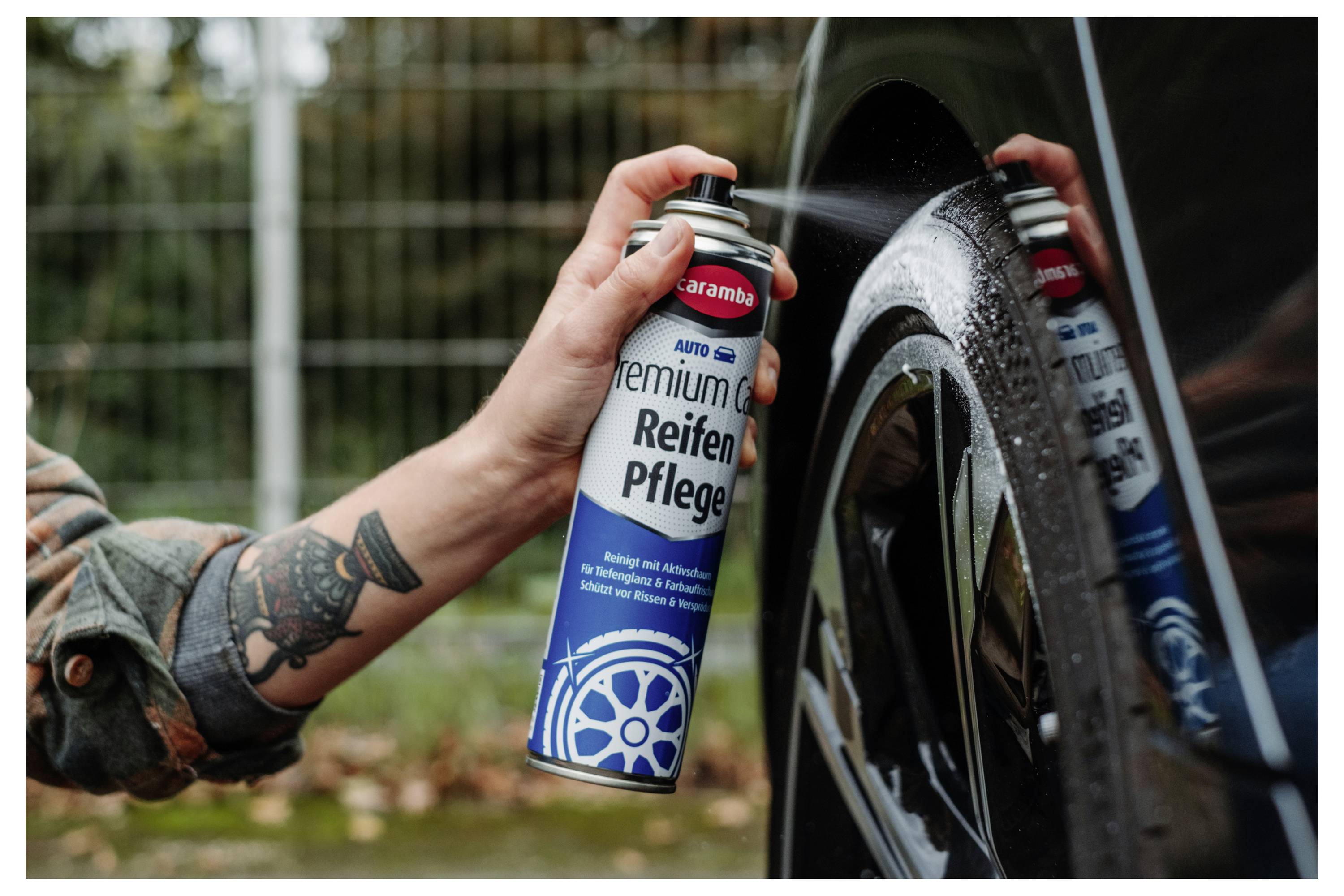 Person sprüht „Kraft Aktivreiniger" aus einer Flasche, während sie eine Oberfläche mit einem blauen Tuch im Freien abwischt.