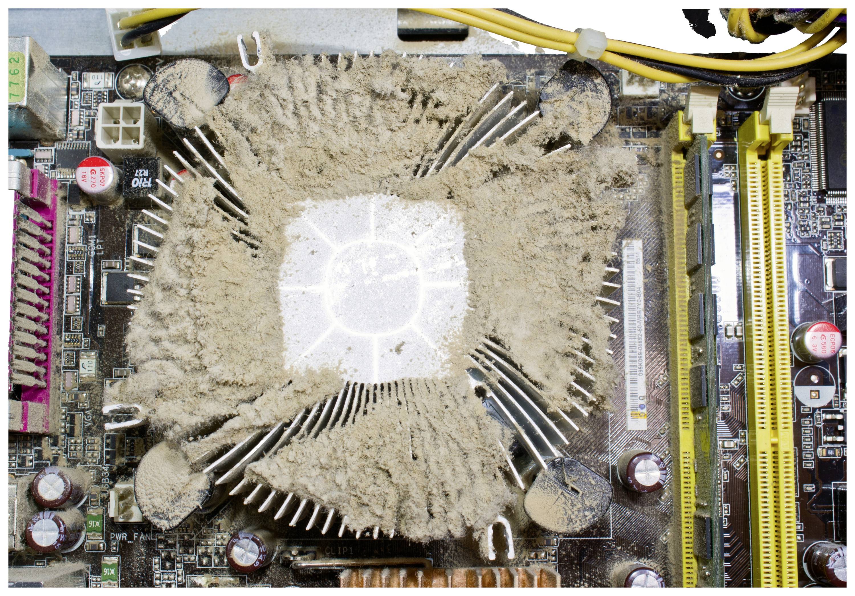 Staubige Lüfter auf einer Computerplatine, behindert die Kühlung. Steckplätze, Kabel und andere Komponenten sind sichtbar.