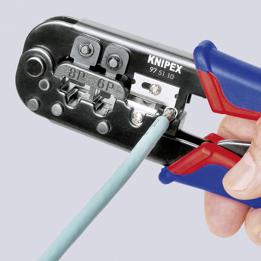 Hand hält eine Crimpzange, die einen Kabelstecker zusammendrückt. Zange hat eine graue und rote Griffkombination.
