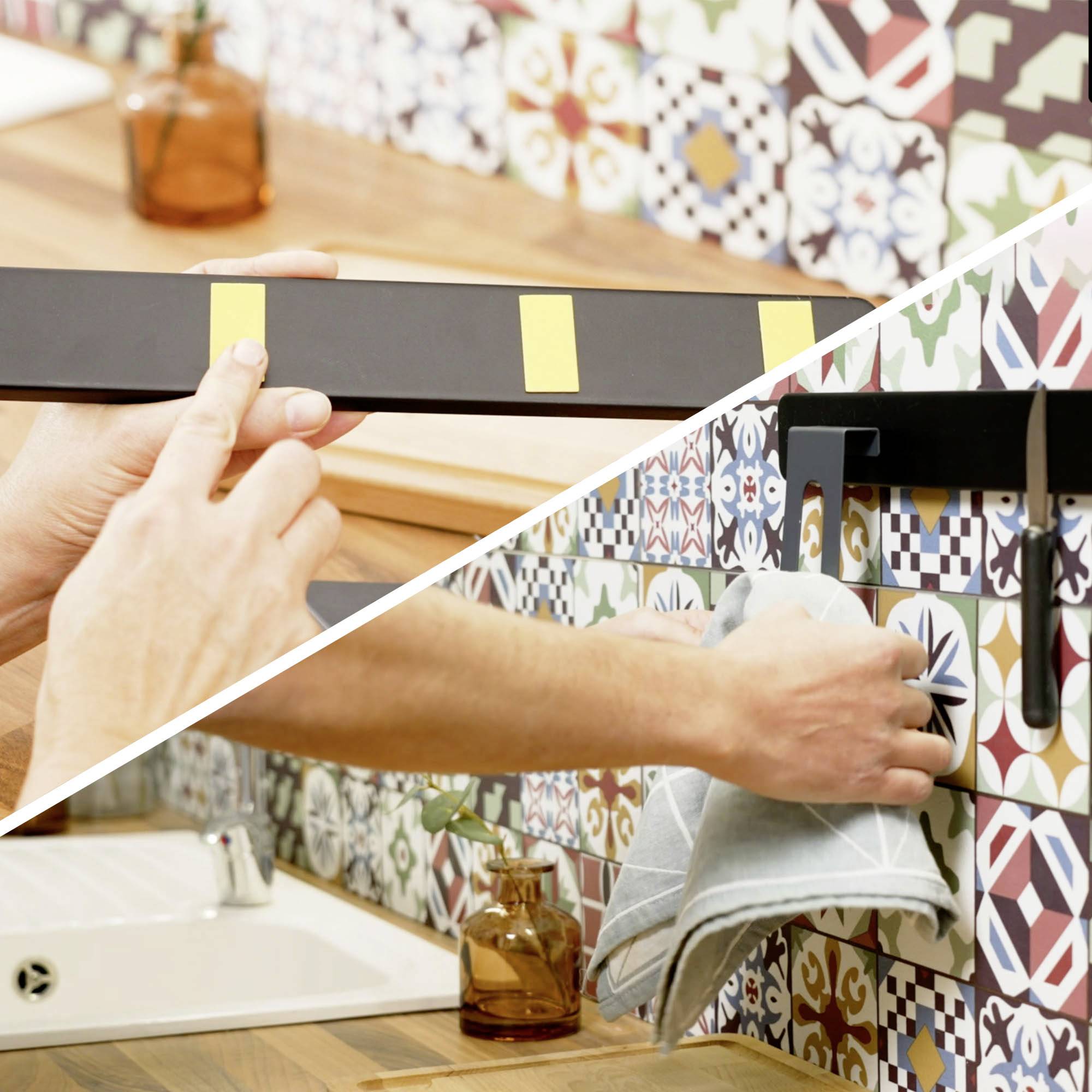 Eine Person, die einen Magnetstreifen an eine Fliesenwand in einer Küche anbringt, während eine andere Person ein Messer und ein Handtuch daran aufhängt und damit die Küchenorganisation demonstriert.