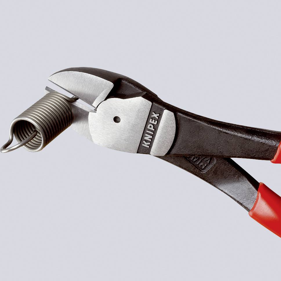 Technikzange mit rotem Griff, geöffnete Greifbacken halten eine Metallfeder. Werkzeug hat Aufschrift 'KNIPEX'.