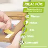 Eine Hand zieht Klebeband von einem Holzrahmen. Text: 'Ideal für: saugende und nicht saugende Untergründe' mit Symbolen für Fliesen, Metall, Holz, Stein, Kunststoff.