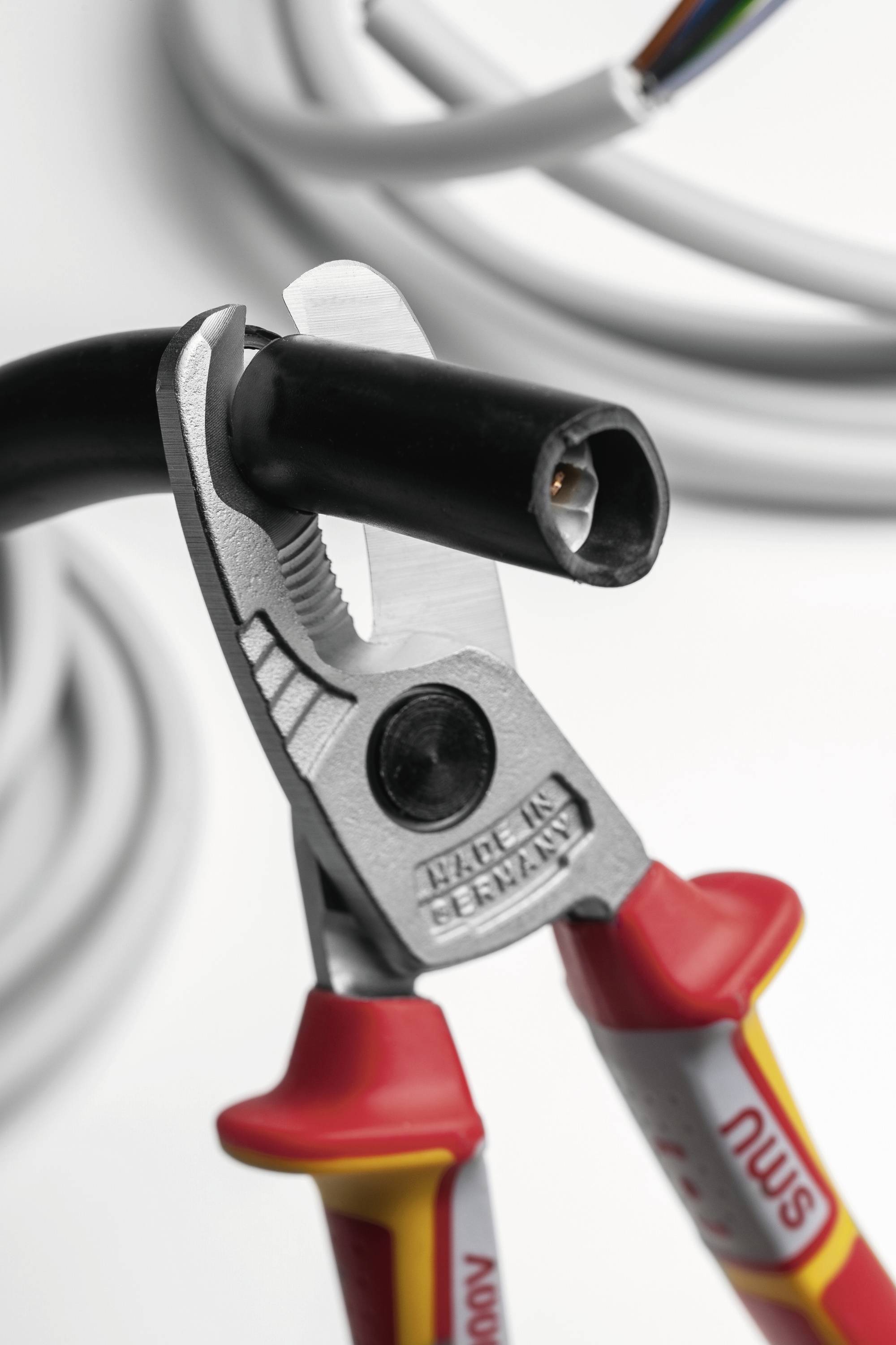 „Nahaufnahme eines isolierten Kabels, das mit Kabeldrahtschneidern durchtrennt wird, mit Betonung auf Sicherheit und Präzision bei elektrischen Arbeiten."