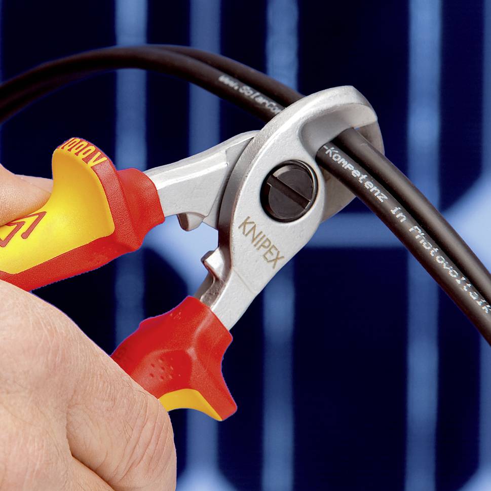 Eine Hand hält einen Kabelschneider der Marke Knipex, der dabei ist, ein dickes Kabel vor einer blau schattierten Oberfläche zu durchschneiden.