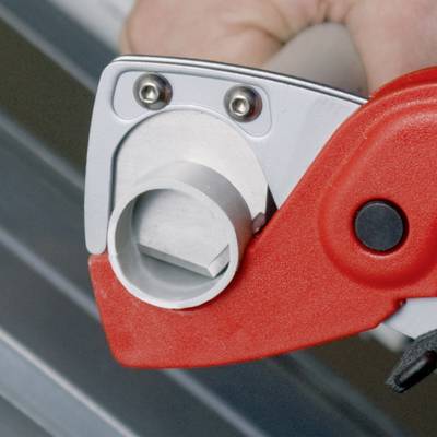 Nahaufnahme eines roten Rohrschneiders in Aktion, der ein Metallrohr schneidet. Eine Hand hält das Werkzeug.