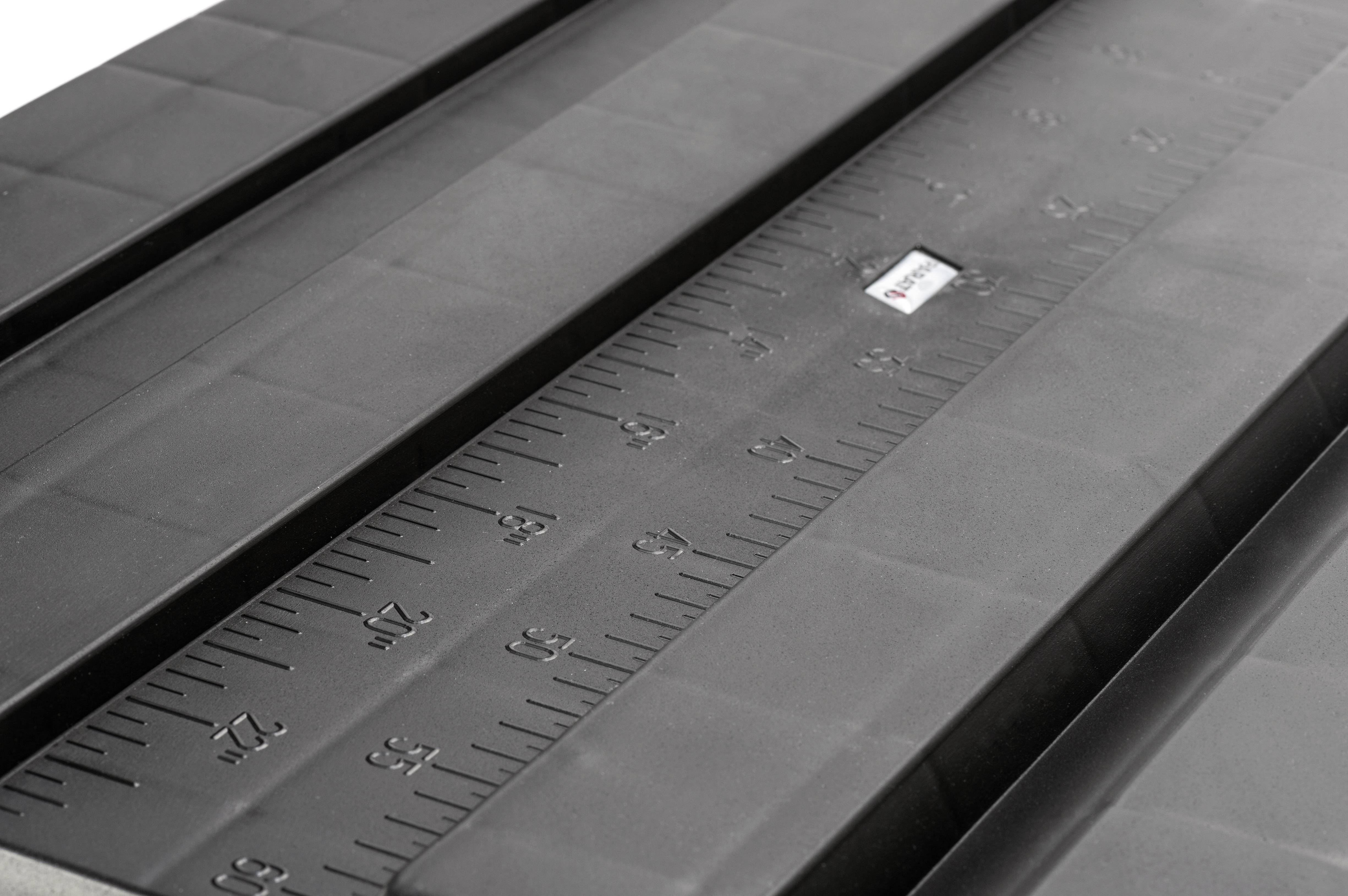 Ein schwarzes Lineal mit Zentimeter- und Zollmarkierungen, das auf einem Tisch liegt.