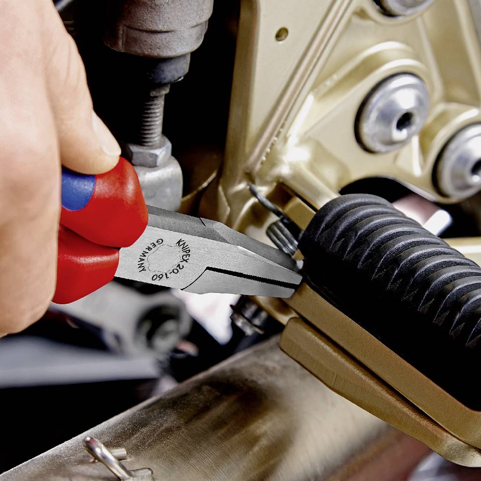 Ein Mechaniker hält eine rote Zange, um eine Schraube an einer goldenen mechanischen Vorrichtung anzuziehen. Fokus auf präzise Arbeit.