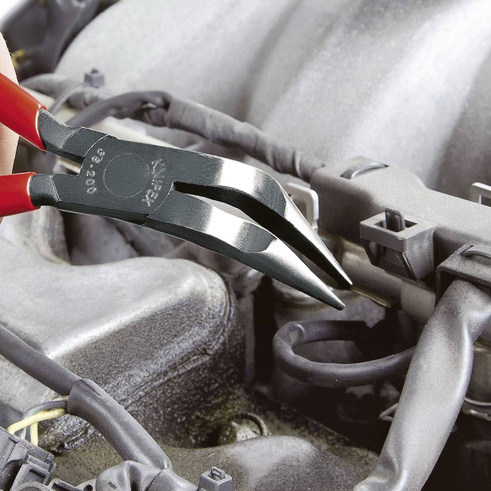 Nahaufnahme einer roten Spitzzange, die ein kleines Teil in einem Automotorfach hält.