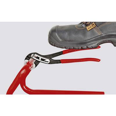 Ein Schuh drückt einen roten Knipex Zangenschlüssel auf eine Rohrverbindung, um sie festzuziehen.