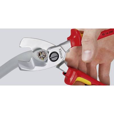 Eine Hand hält eine rote und gelbe Kabelschneiderzange, die ein Kabel mit mehreren Drahtadern durchtrennt.