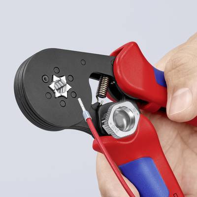 Eine Hand hält eine rote Crimpzange, die einen Draht mit einem Metallstecker bearbeitet.