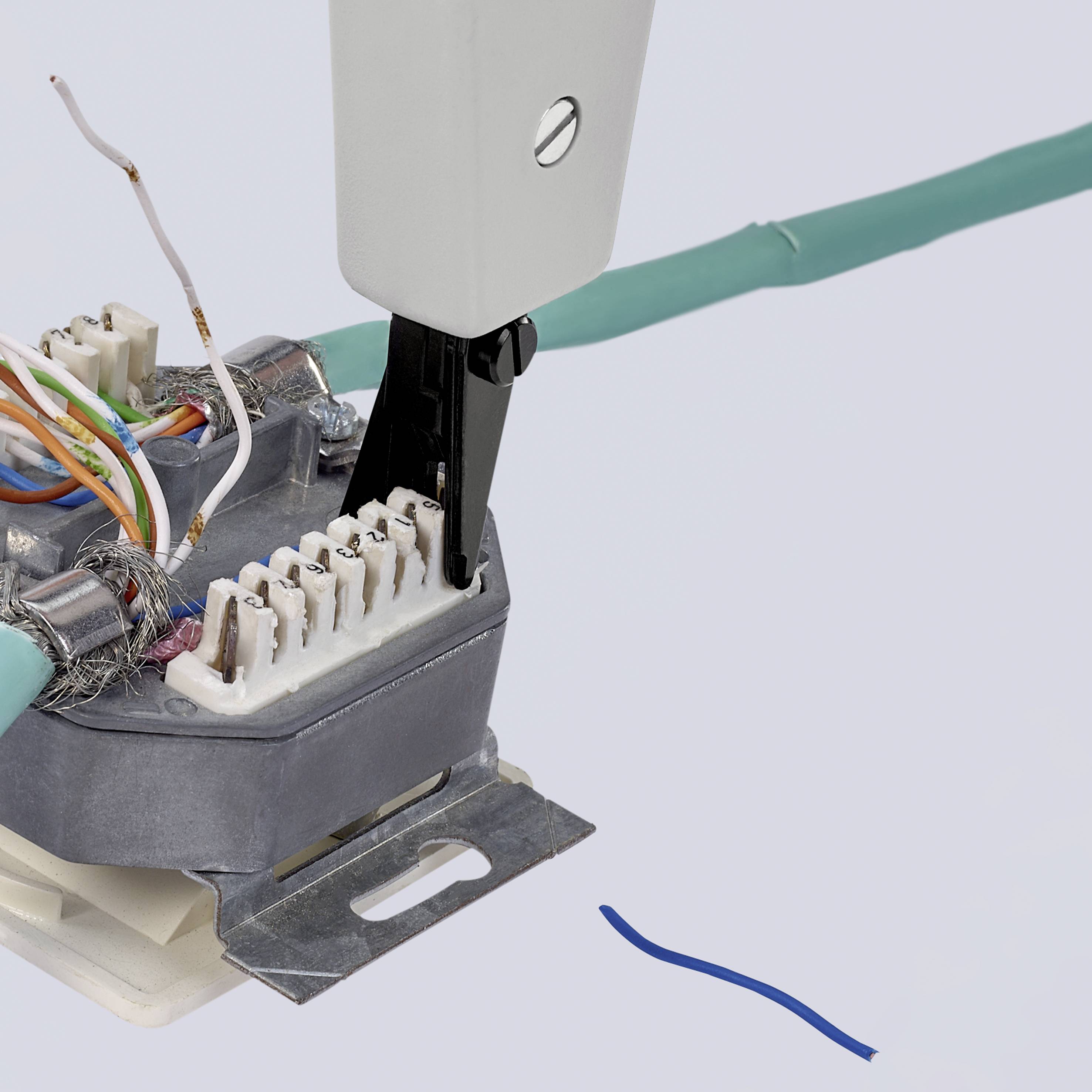 Ein Elektrokabel wird mit einer Klemme verbunden. Mehrere bunte Drähte sind sichtbar, einige davon sind abisoliert.