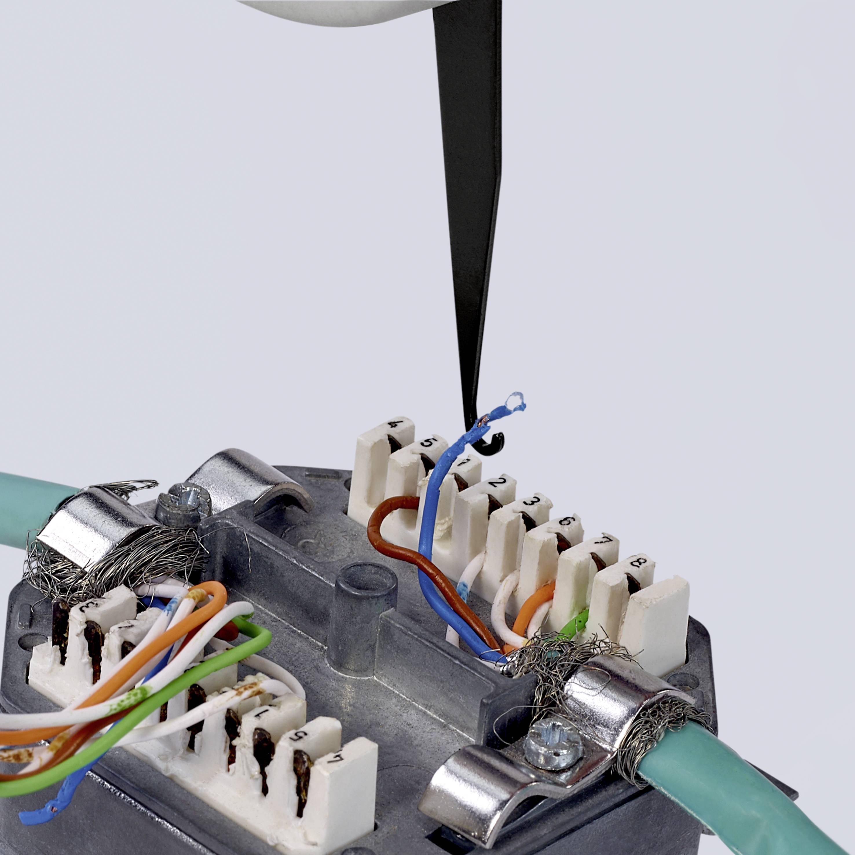 Ein Schraubendreher öffnet einen elektrischen Verteilerkasten. Mehrere farbige Drähte sind sichtbar und miteinander verbunden.