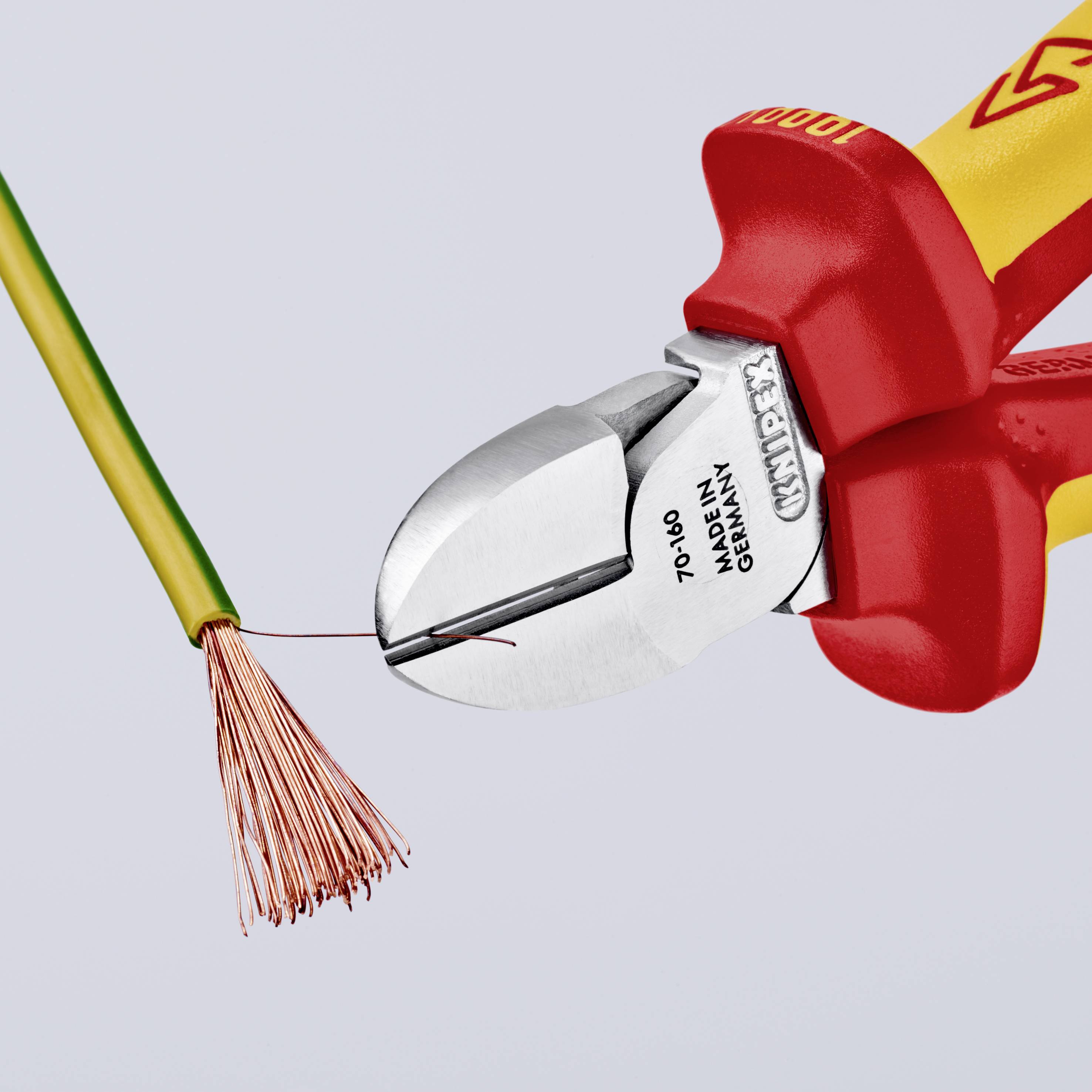 Ein Kabelschneider schneidet durch ein grün-gelbes Kabel. Der Schneider hat rote Griffe und silberne Klingen.