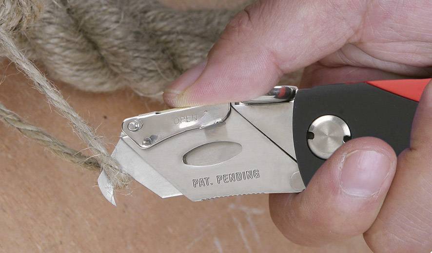 Ein Messer schneidet ein dickes Seil. Eine Hand hält das Messer fest.