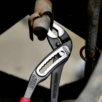 Eine Wasserpumpenzange greift einen Metallbolzen. Die Zange trägt den Aufdruck 'Knipex'. Sie wird in einer Reparatursituation verwendet.