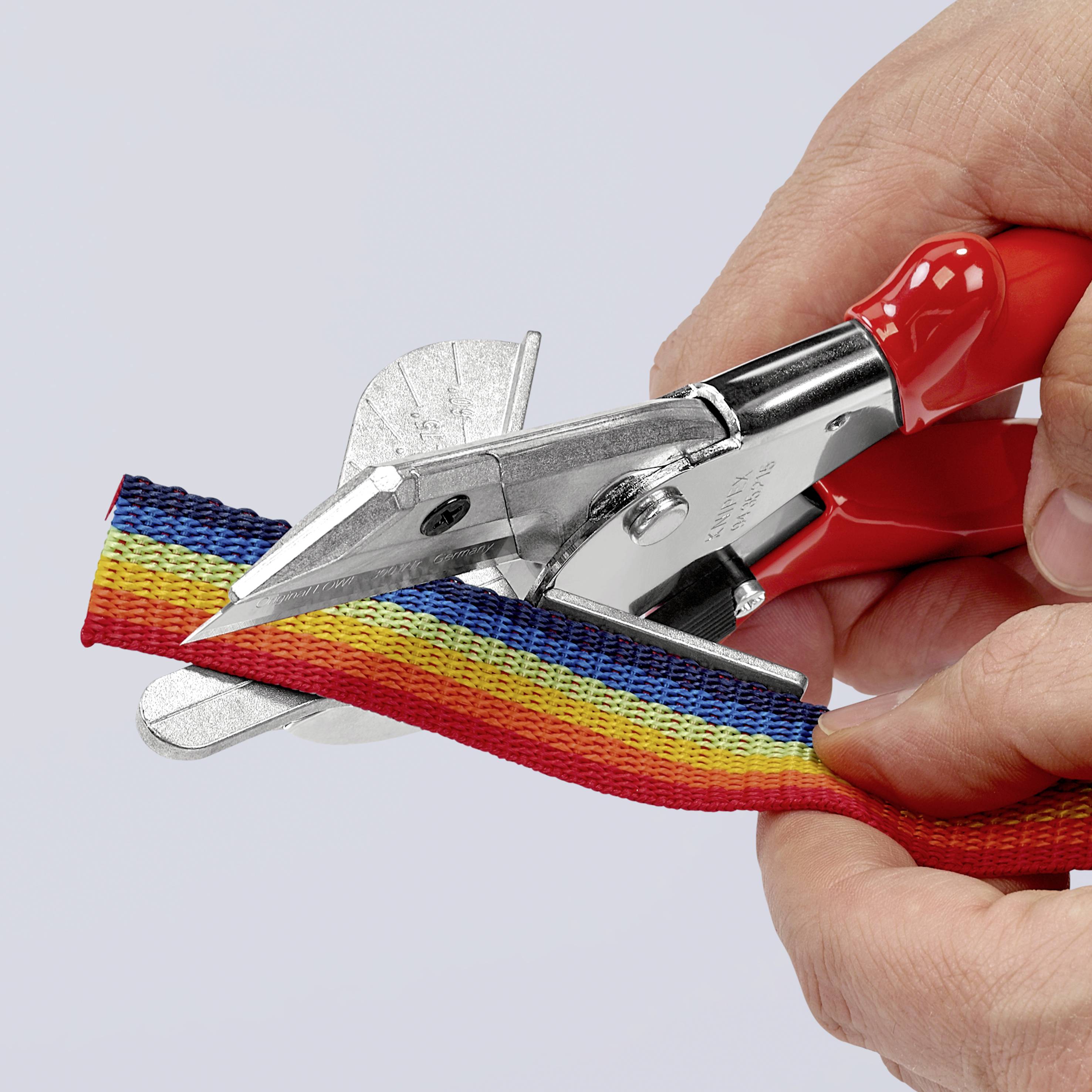 Eine Hand schneidet mit einer roten Schere durch ein regenbogenfarbenes Band.