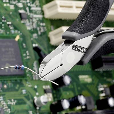 Eine Drahtschneiderzange schneidet einen blauen Widerstand über einer grünen Platine mit sichtbarer Elektronik.