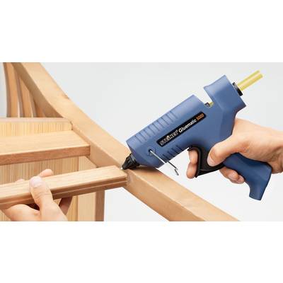 Eine Person klebt mit einer blauen Heißklebepistole zwei Holzteile zusammen.