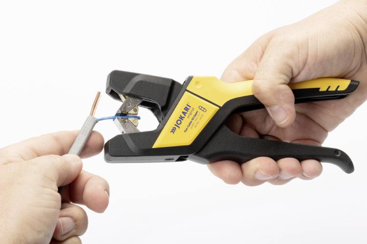 Eine Person verwendet eine gelb-schwarze Kabelabisolierzange, um die Ummantelung von einem grauen Kabel zu entfernen.