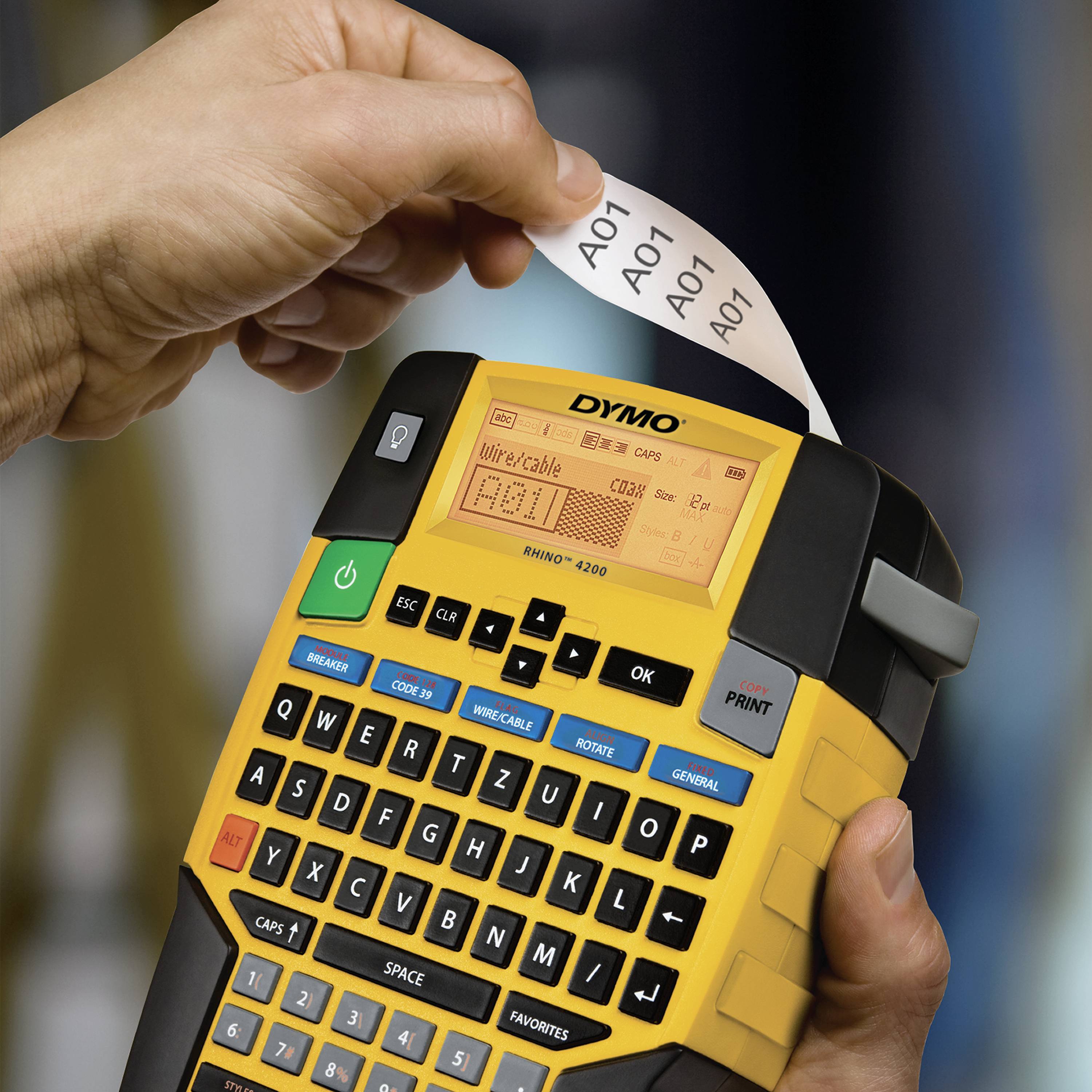 Eine Hand hält ein Etikettiergerät mit bunten Tasten und druckt ein Etikett mit der Aufschrift 'A01' aus.