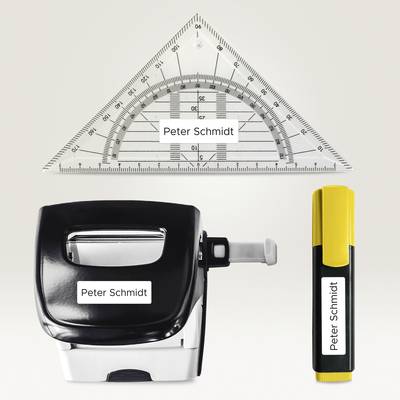 'Dreieck-Lineal, Stempel und Textmarker mit dem Namen "Peter Schmidt" beschriftet, auf einem hellen Hintergrund angeordnet.'