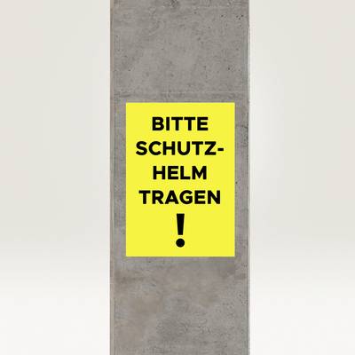 Betonsäule mit gelbem Schild und schwarzem Text 'BITTE SCHUTZHELM TRAGEN!', wichtiger Sicherheitshinweis.