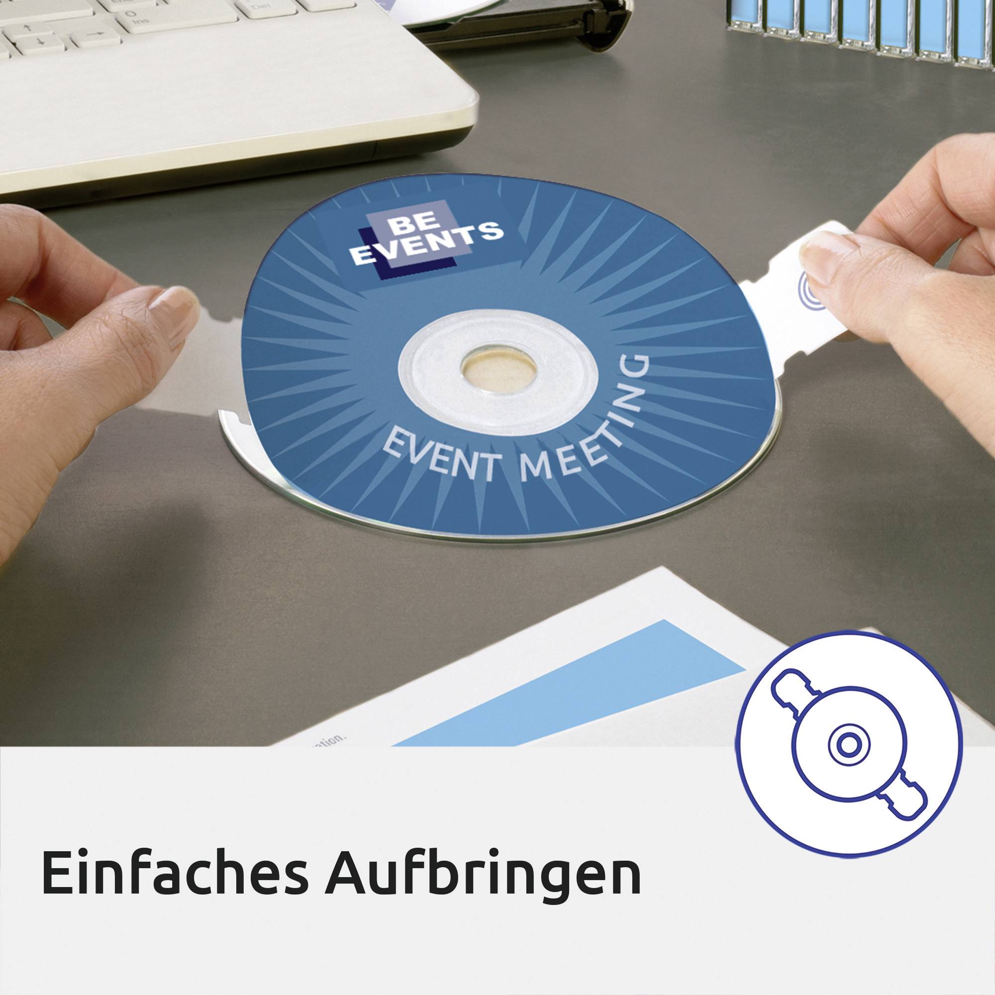 Zwei Hände platzieren eine runde blaue Karte mit 'Event Meeting' und 'BE Events' auf einen weißen Untergrund. Oben links ein Laptop.