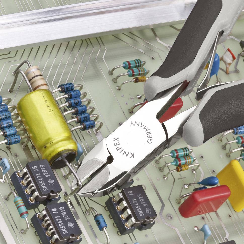 Eine Zange greift in eine Leiterplatte mit elektronischen Bauteilen wie Widerständen und Mikrochips, symbolisiert Reparatur oder Montage.