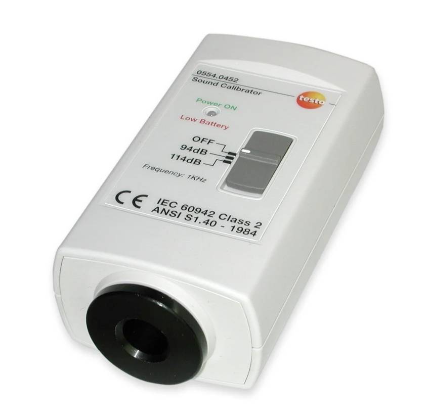 Ein weißer Soundkalibrator mit Einstellrädern und Schaltern, die den Stromstatus, Dezibel-Optionen (94 dB, 114 dB) und Frequenznotizen anzeigen.