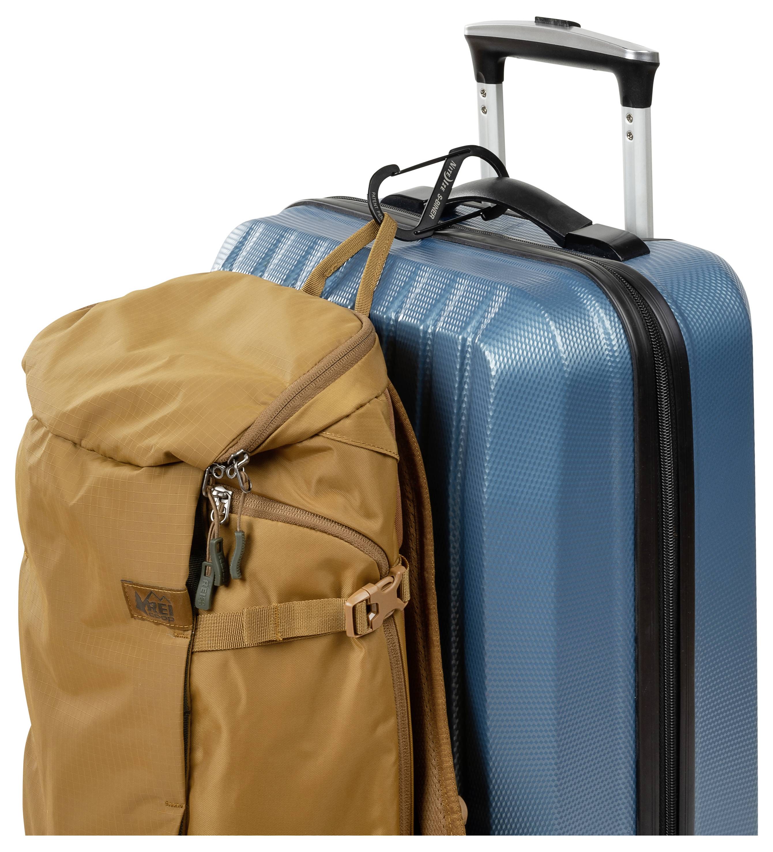 Ein blauer Hartschalenkoffer mit einem Teleskopgriff und einem braunen Rucksack, der daran befestigt ist, beide reisefertig.
