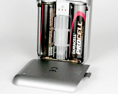 Ein geöffnetes Batteriefach mit zwei eingelegten AA-Batterien und einer entfernten Abdeckung, zeigt die Innenansicht eines Geräts.